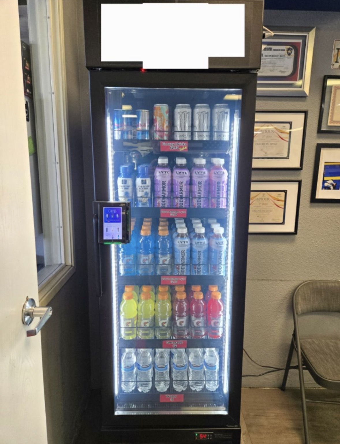 Glass-front beverage cooler stocked with sports drinks and energy drinks at a local gym